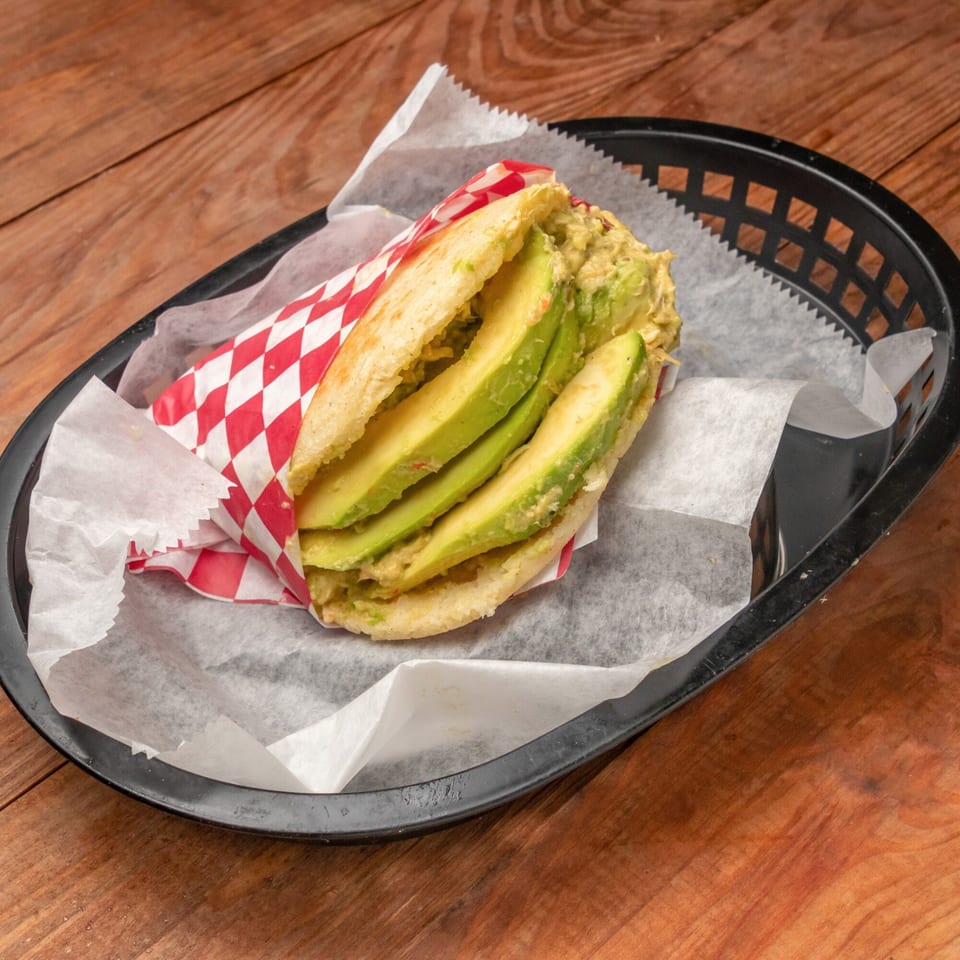 Venezuelan Reina Pepiada arepa with sliced avocado and chicken salad in a basket.