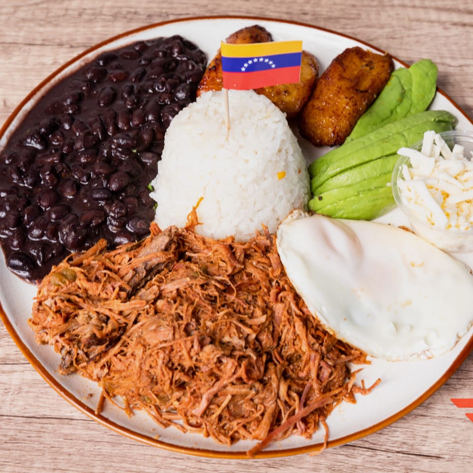 Venezuelan Pabellón Criollo with shredded beef, black beans, rice, plantains, avocado, and a fried egg.