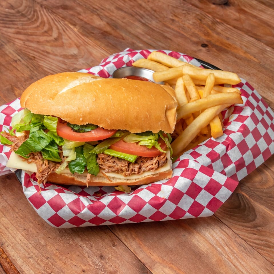 Venezuelan shredded beef sandwich with lettuce, tomato, and cheese, served with fries and ketchup.
